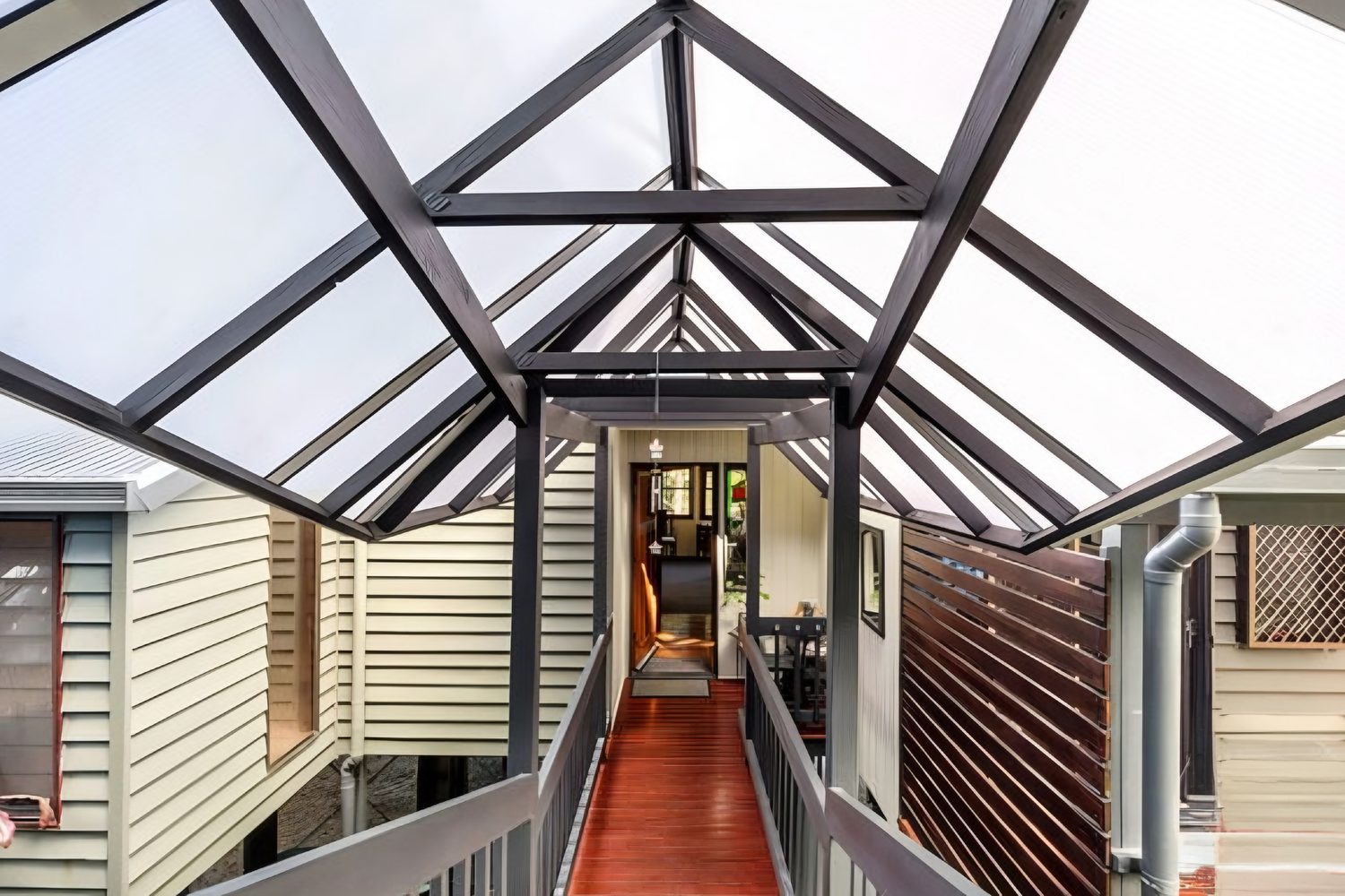 Covered walkway with exposed timber roof framing linking two wings of a Queensland home